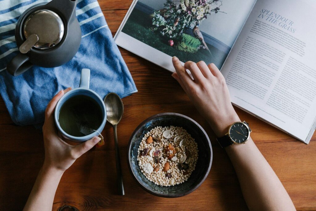 Manos sujetando una taza de café sobre una revista abierta
